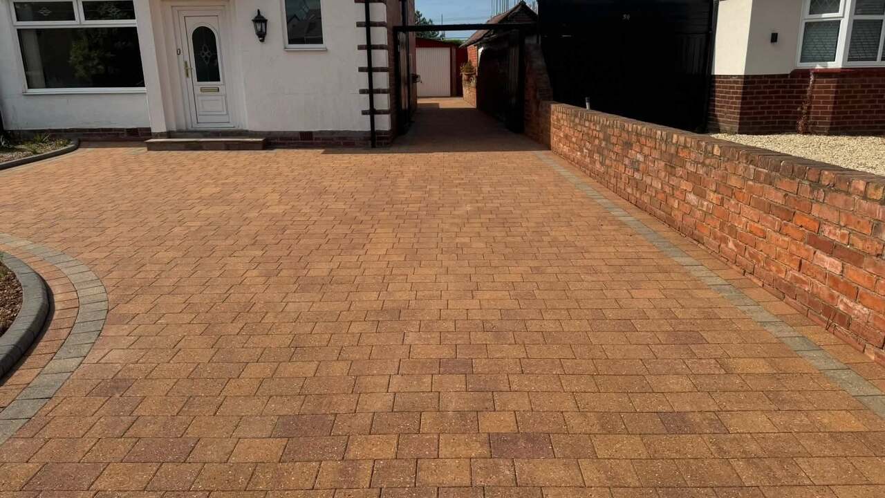 A block-paved driveway after cleaning, in front of a white house